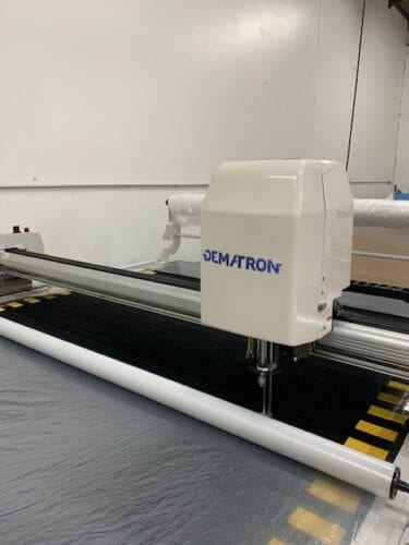 A machine is cutting fabric on the table.